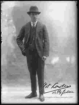 Foto de estudio de un varón de traje con un sombrero.