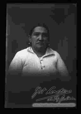 Foto de estudio con esfumador de una chola sin sombrero. Lleva puesto una chompa abierta con botones y aretes