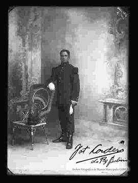 Foto de estudio de un Militar con uniforme francés, apoyado en una silla de mimbre