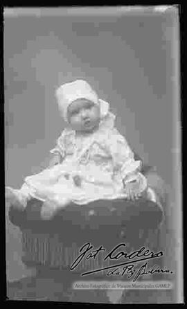 Foto de estudio de una niña pequeña, sentada en la cabecera de un sillón