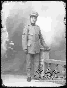 Foto de estudio de un soldado, parado junto a la columna de una baranda