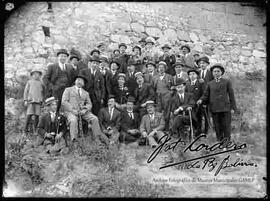 Grupo de varones, reunidos en el patio de una casa particular, festejando un acontecimiento con un grupo de música.