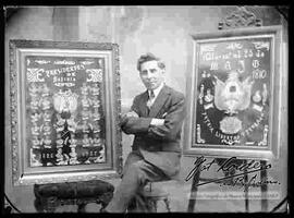 Foto de estudio de un pintor sentado en medio de dos cuadros: Cuadro mosaico de los presidentes de Bolivia y cuadro con el escudo de Argentina.