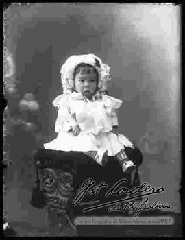 Foto de estudio de una niña pequeña sentada encima de un sillón