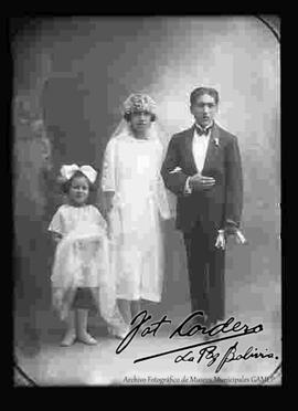 Foto de estudio de una pareja de novios, en el día de su matrimonio junto a una niña
