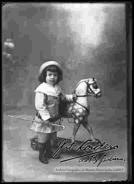 Foto de estudio de una niña a lado de un caballito de juguete