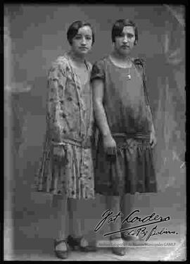 Foto de estudio de dos damas (hermanas), que lucen puestos diferentes vestidos.