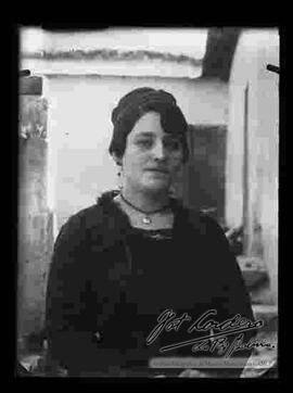 Reproducción fotográfica de una dama que se encuentra en el pasillo de una casa y que presenta un modelo de peinado.