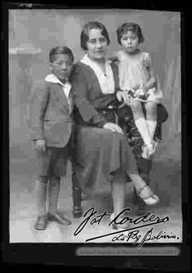 Foto de estudio de una madre, sentada junto a sus dos hijos pequeños