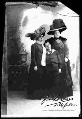 Foto de estudio de dos damas y una niño, llevan puesto un modelo de sombrero.