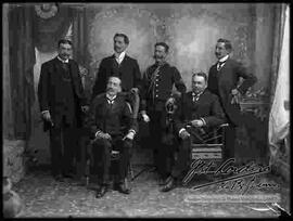 Foto de estudio de un grupo de varones de bigote y vestidos de traje.