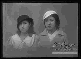 Foto de estudio de medio cuerpo de dos damas que llevan puestos dos modelos de sombreros.