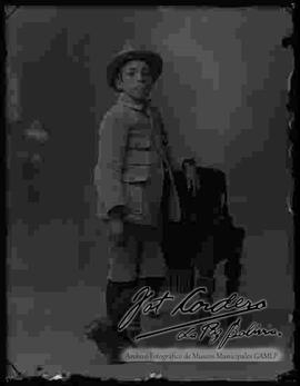 Foto de estudio de Julio Cordero Ordoñez de niño, parado junto a un sillón