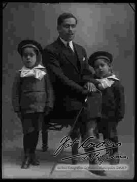 Foto de estudio de una familia. un padre sentado en un sillón junto a sus dos hijos pequeños