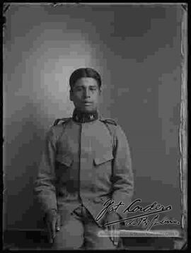 Foto de estudio de un cadete, músico de la banda del Colegio Militar sentado