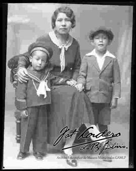 Foto de estudio de una madre , sentada junto a sus dos hijos pequeños