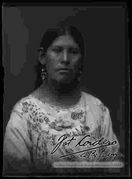 Foto de estudio de medio cuerpo de una chola que lleva puesto una blusa, aretes y un collar