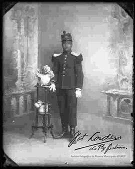 Foto de estudio de un Militar, apoyado a una mesita con flores