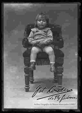 Foto de estudio de una niña que se encuentra sentada en un sillón.