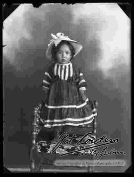 Foto de estudio de una niña pequeña, parada encima de una silla tallada