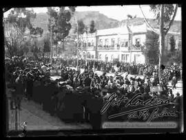 Desfile de señoritas estudiantes de diferentes colegios, pasando en carros alegóricos, frente a una multitud de personas concentradas por el paseo el prado