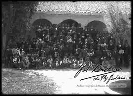 Grupo de niños, jóvenes y adultos en el día de su primera comunión, junto a un cura  franciscano en el interior del convento de San Francisco