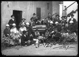Familia, reunida en el patio de una casa particular, celebrando carnavales con música de estudiantina