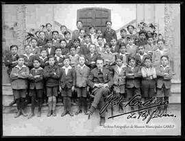 Grupo de estudiantes en gradas del colegio San Calixto, delante de un salon de clases junto a su profesor