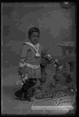 Foto de estudio de un niño apoyado a un pequeño barandal.