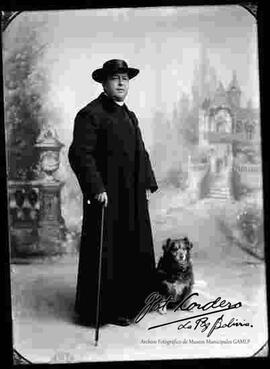 Foto de estudio de un sacerdote de pie  junto a su perro