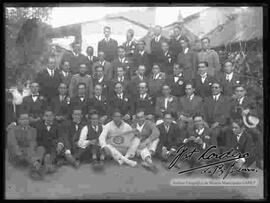 Grupo de varones, reunidos en el patio de una casa por la celebración de carnavales.