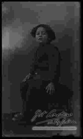 Foto de estudio de una niña que se encuentra sentada encima de un sillón