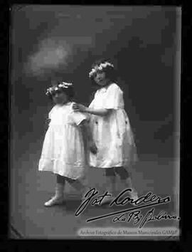 Foto de estudio de dos niñas vestidas de blanco con flores en el cabello