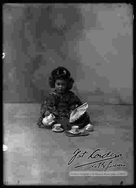 Foto de estudio de una niña vestida de chinita, sirviendo te.