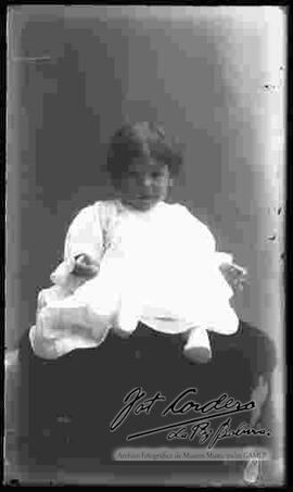 Foto de estudio de una niña que se encuentra sentada en la cabecera de un sillón