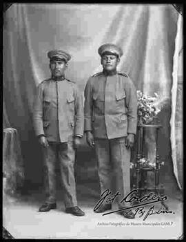 Foto de estudio de dos Militares junto a una mesita con flores