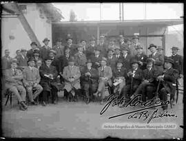 Grupo de varones vestidos de traje y sombrero, reunidos  en el patio de una casa particular