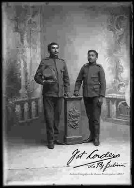 Foto de estudio de dos soldados apoyados con la mano a una pequeña columna