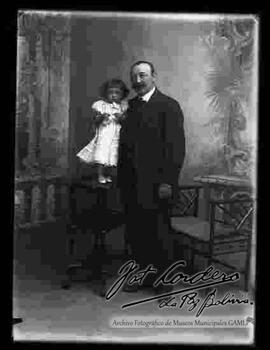 Foto de estudio de un padre sosteniendo a su hija pequeña que se encuentra parada encima de una mesita
