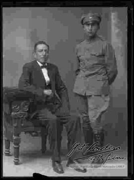 Foto de estudiod e un soldado de la Guerra del Chaco  junto a su padre, que se encuentra sentado a su lado en un sillón