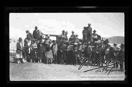 Grupo familiar, posando delante de carro, junto a un cura