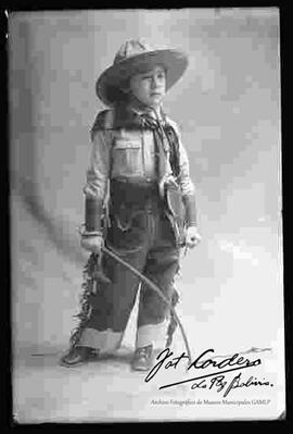 Foto de estudio de un niño disfrazado de vaquero con su látigo.