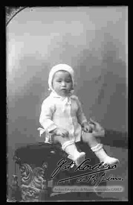 Foto estudio de una niña pequeña, sentada en la cabecera de un sillón