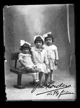 Foto de estudio de tres niñas sentadas en una banca