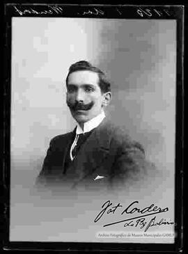 Foto de estudio con esfumador de un varón de bigote que viste de traje.