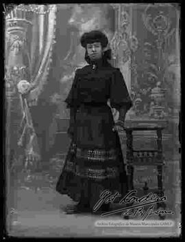 Foto de estudio de una dama que luce un vestido largo y guantes de seda.