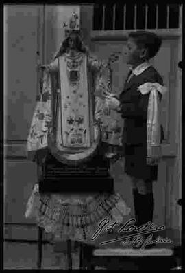 Un niño con ropa de primera comunión junto a la imagen de la Virgen de la Merced.