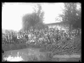 Grupo de varones, reunidos en el patio de una casa, detrás de un charco de agua, por la celebración de carnavales.