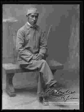 Foto de estudio de un soldado de la Guerra del Chaco, sentado en una banca