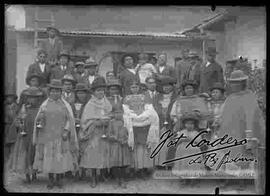 Familia  en el patio de una casa, donde varias cholas sostienen candeleros y mostrando joyas